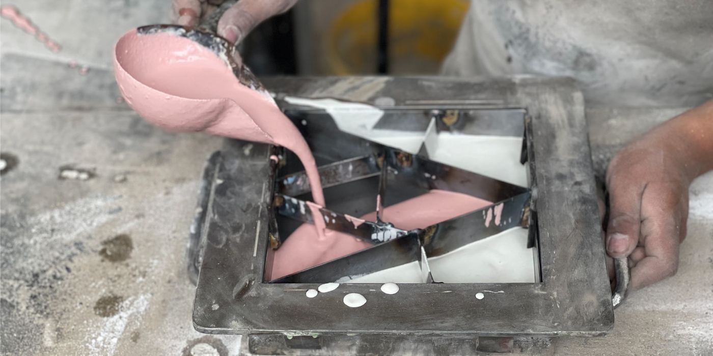Artesano vertiendo pigmento rosado dentro del molde de una baldosa hidráulica