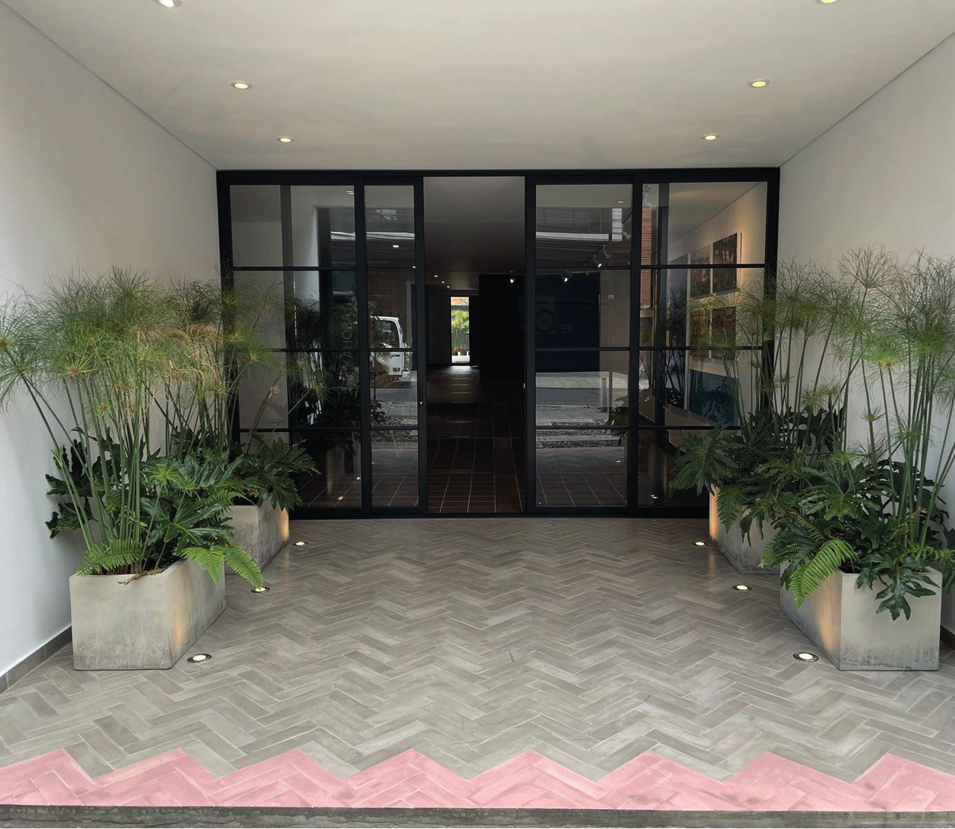 Lobby de edificio con piso de baldosa gris en espiga y franja rosada