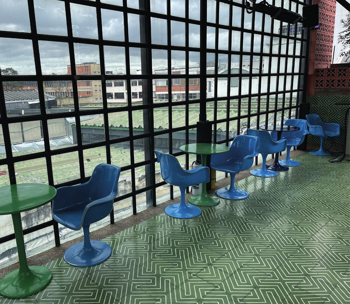 Terraza de restaurante con piso verde en espiga y sillas azules